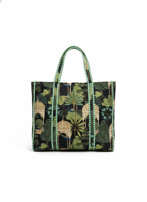 Tote bag with green leaf and castle pattern on a black background.
